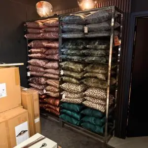 Rows of patterned throw pillows stacked on a metal display rack in a shop, with sale price tags visible