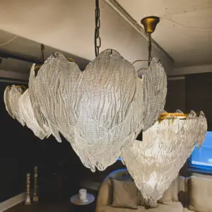 Row of ribbed glass pendant lights hanging from black chains in a dim room, with a sofa and small side table beneath them