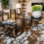 Living room decor: black glass coffee table with gold vases, a crystal cluster, a Rolex book, and a large white pot of green hydrangeas nearby.