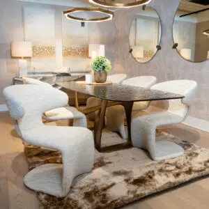 Modern seating area with light gray curved chairs around a round glass table on a beige shag rug in a stylish showroom setting
