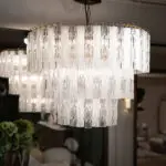 Close-up of a modern crystal chandelier with multiple clear glass prisms hanging in rows, reflecting light.