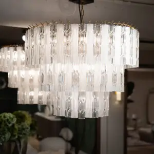 Close-up of a modern crystal chandelier with multiple clear glass prisms hanging in rows, reflecting light.