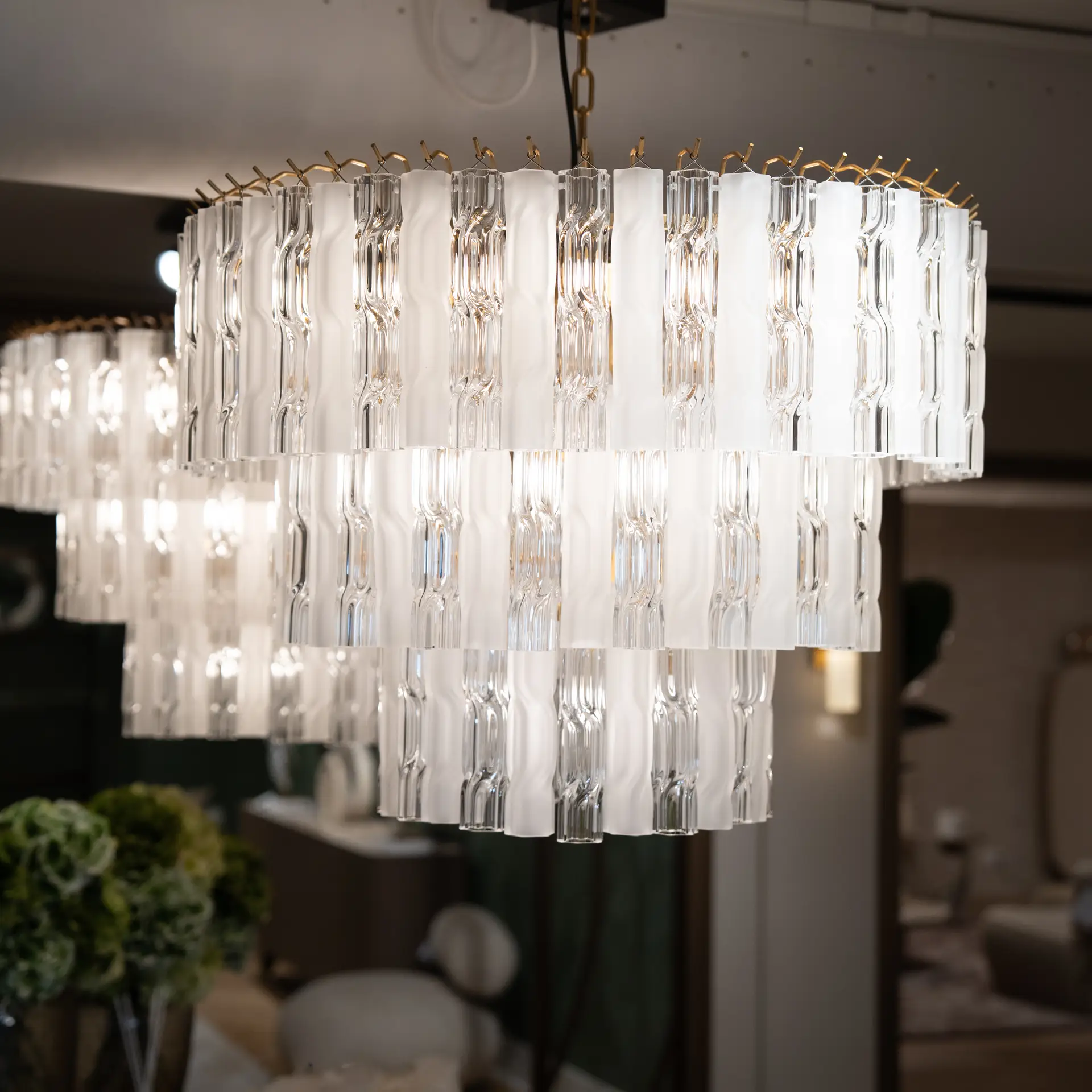 Close-up of a modern crystal chandelier with multiple clear glass prisms hanging in rows, reflecting light.