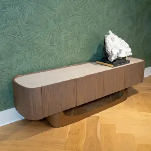 Rock crystal specimen on a metal stand atop a wooden curved cabinet against a textured green geometric wall.