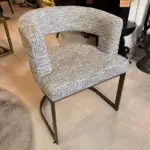 A tweed upholstered armchair with curved back and metal sled legs in a showroom setting