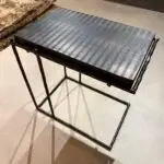 Industrial metal console table with a perforated steel top and angled legs in a modern style.