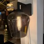 Close-up of a black wall sconce with a large glass globe housing an Edison bulb.