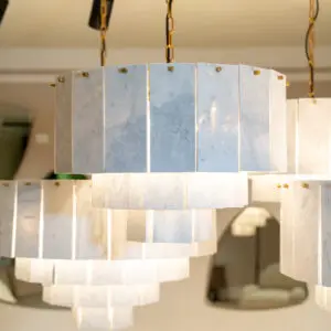 White marble rectangular panels hanging from gold chains, forming a modern chandelier-like installation.