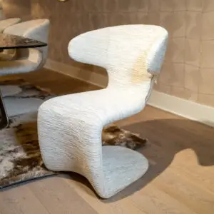 Close-up of a light beige fabric armchair with a curved armrest in a modern living area.