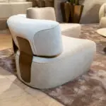 Close-up of a pale blue curved lounge chair in a modern seating area, with a marbled floor and carpet in the background.