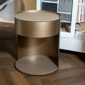 Bronze metallic pedestal with a circular top on a wooden showroom floor.