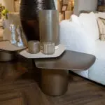 Showroom display of tall textured vases on a gray table with a white sofa in the background
