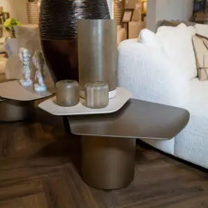 Showroom display of tall textured vases on a gray table with a white sofa in the background