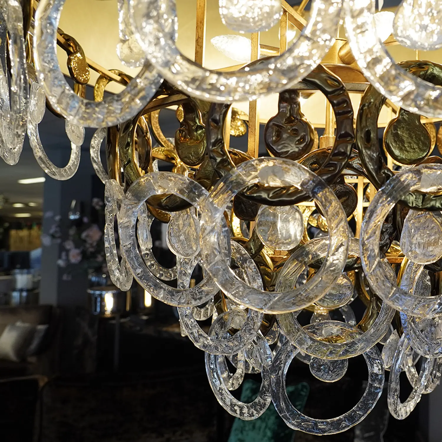 Close-up of a crystal chandelier with interlocking clear glass rings and a gold metal frame.