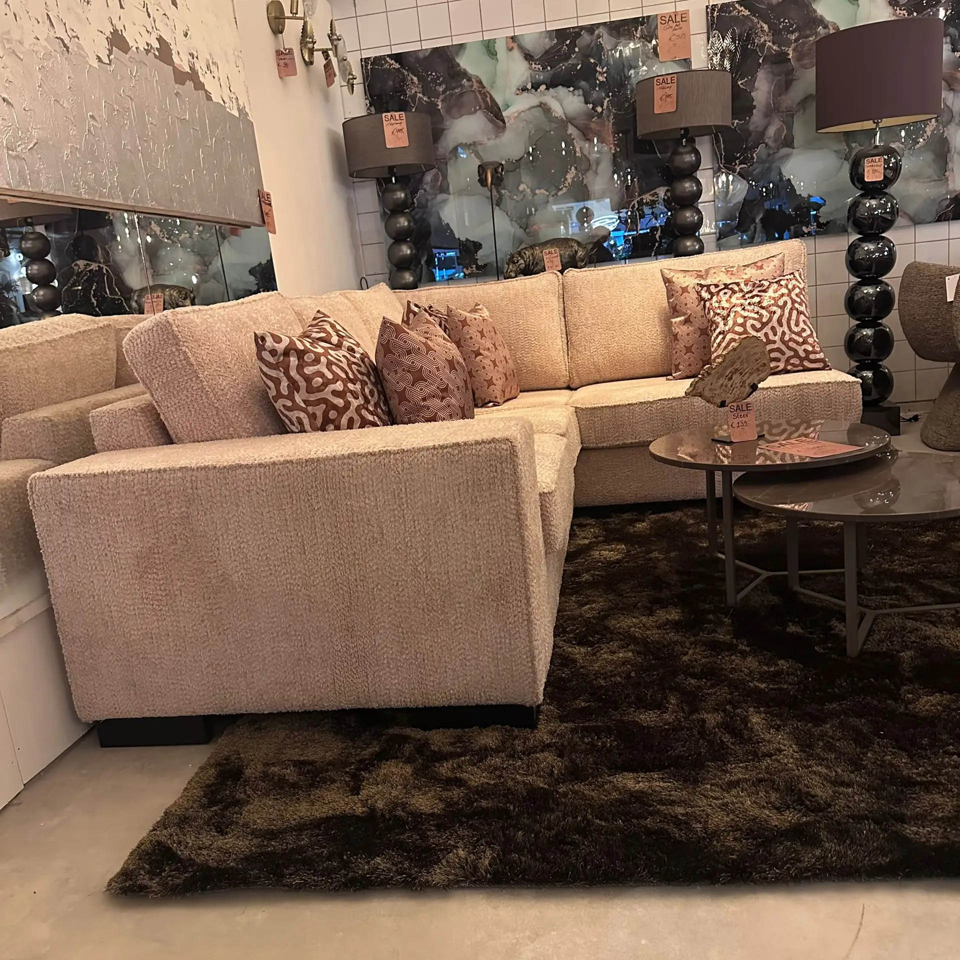 Beige sectional sofa with patterned throw pillows in a furniture store display.