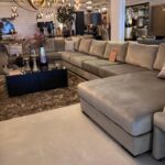L-shaped gray sectional sofa in a showroom with a black glass coffee table and a sale flyer on the sofa