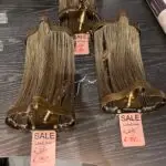 Brown metal-framed chandelier with gold beaded fringe on display; sale tag shows €150.