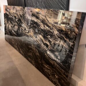 Large black marble slab with white and gold veining propped against a wall in a showroom.