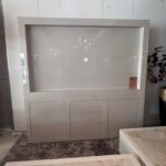 Large white display cabinet with a recessed center panel and a small circular knob, in a showroom.