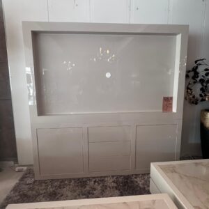 Large white display cabinet with a recessed center panel and a small circular knob, in a showroom.