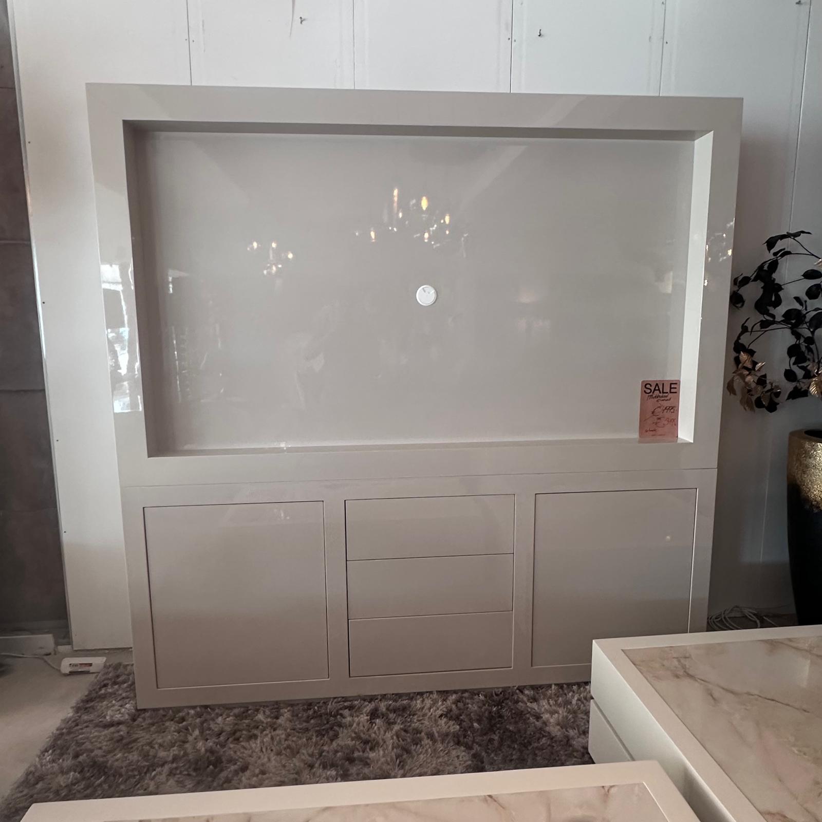 Large white display cabinet with a recessed center panel and a small circular knob, in a showroom.