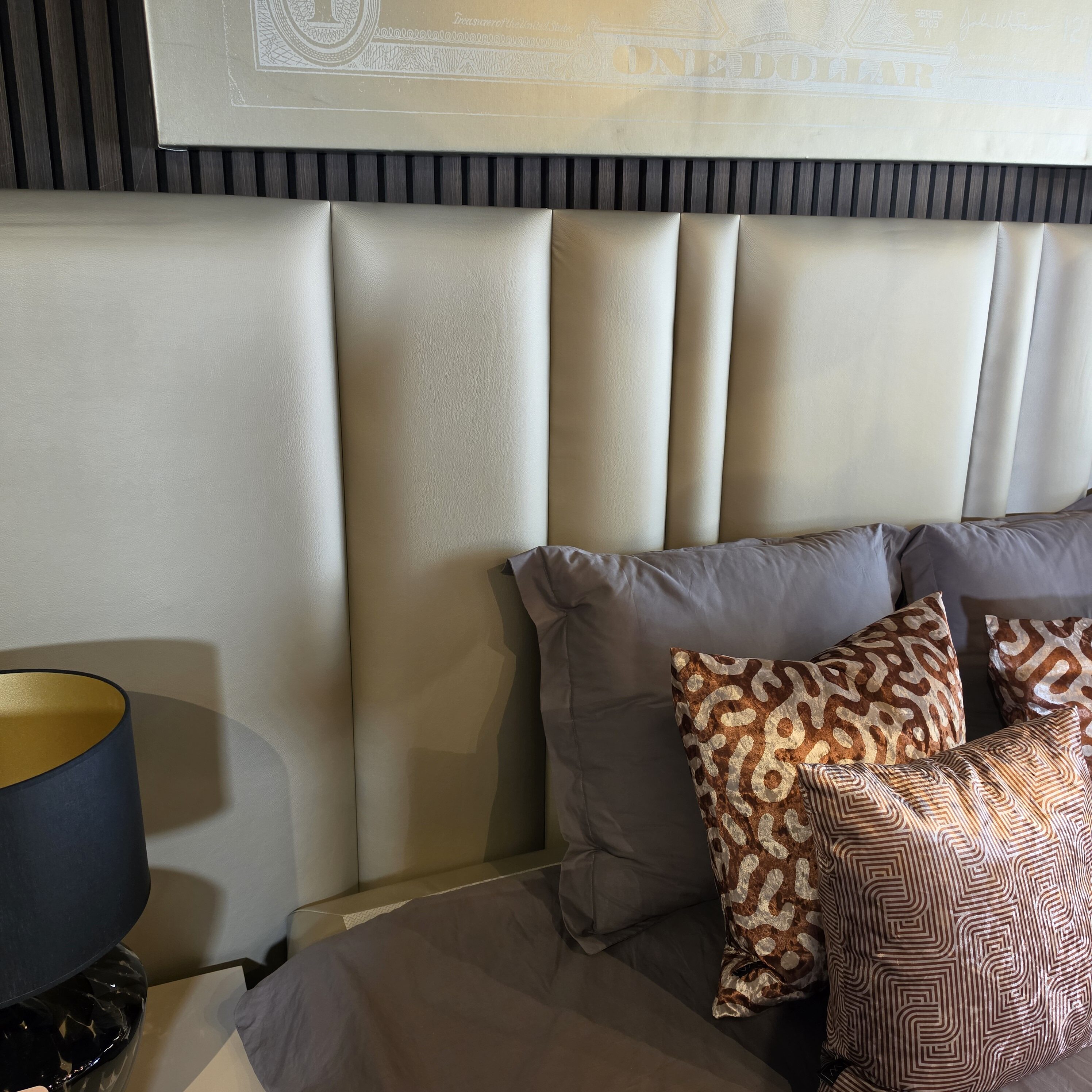 Beige upholstered booth-style seating with brown patterned throw pillows against a dark wooden slat wall in a modern room.